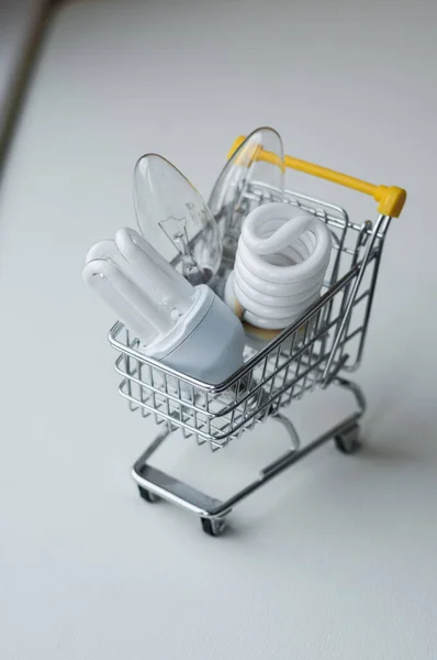 İçinde ampuller olan alışveriş arabası. Ahşap arka planda akıllı bir konsept satın al. Alışveriş arabası.