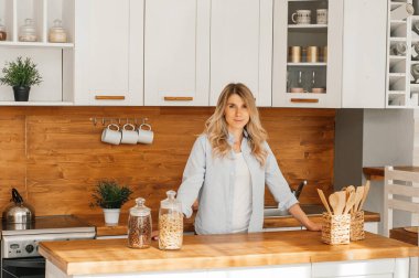 Mutfakta balık pişirirken genç ve mutlu bir bayanın görüntüsü. Kameraya bakıyorum..