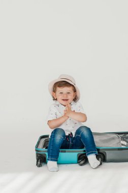 Mutlu çocuk. Büyük Blau tekerlekli bavul tekerlekli tekerlekli tekerlekli valiz çantasının önünde beyaz arka plan üzerinde duruyor. Seyahat konsepti