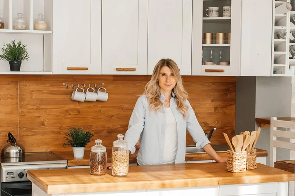 Mutfakta balık pişirirken genç ve mutlu bir bayanın görüntüsü. Kameraya bakıyorum..