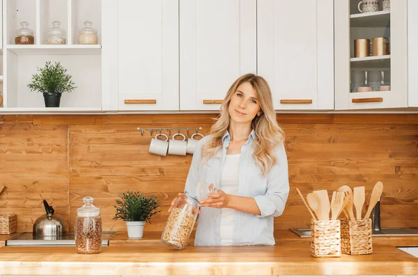 Mutfakta balık pişirirken genç ve mutlu bir bayanın görüntüsü. Kameraya bakıyorum..