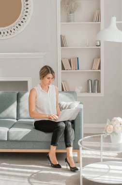 Genç neşeli, mutlu, pozitif ve güzel iş kadınının görüntüsü ofiste dizüstü bilgisayar kullanarak oturuyor..