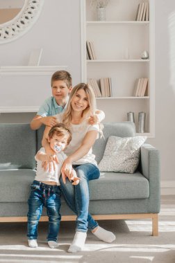 Anne ve çocuk sıcak evde birlikte gülüyorlar. Kanepede dinlenirken birbirlerine sevinçle sarılıyorlar. Ebeveynler şakacı bir şekilde oğlanların ayaklarına dokunuyor ve o bundan zevk alıyor.