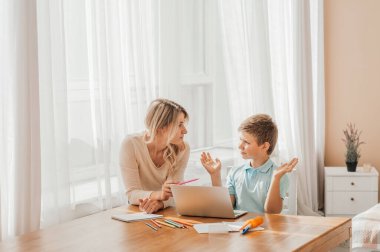 Annem küçük çocuğun ödevlerine yardım ediyor. Anne ve oğul birlikte çiziyor, anne ödevlerine yardım ediyor. Sevimli çocuk annesiyle birlikte okul ödevini yapıyor, evde, bir kitap yazıyor.