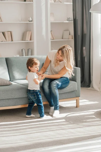 Anne ve çocuk sıcak evde birlikte gülüyorlar. Kanepede dinlenirken birbirlerine sevinçle sarılıyorlar. Ebeveynler şakacı bir şekilde oğlanların ayaklarına dokunuyor ve o bundan zevk alıyor.