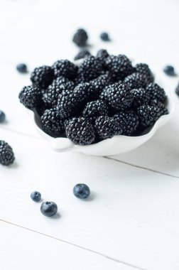 Dağılmış böğürtlen, yaban mersini ve chia tohumlarının panoramik çekimi beyaz ahşap masa üzerinde izole edilmiş siyah