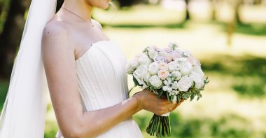 Güzel beyaz elbiseli gelin bir düğün buketi tutuyor, kişi görünmüyor, mesaj için yer