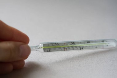 Tıbbi cıva termometreyi tutan bir el.