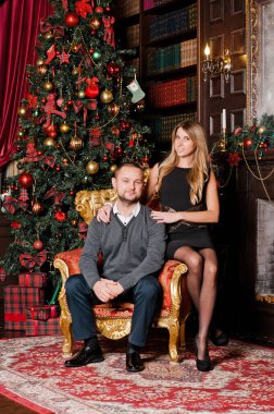 Bir çift Noel ağacının yanındaki kanepede oturuyor ve hediyeler veriyorlar. - Sürpriz. Duygular. Noel