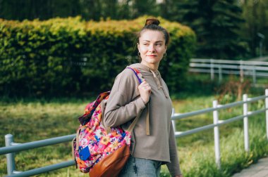 Gün batımında elinde klasörler ve kitaplarla gezen mutlu güzel öğrenci kız.