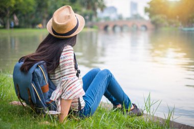 Asyalı kadın turist backpacker bkz: gün batımı. o bir mutluluk vardır. seyahat sırasında. waterfront genel Park'ta. Tatil ve rahatla.