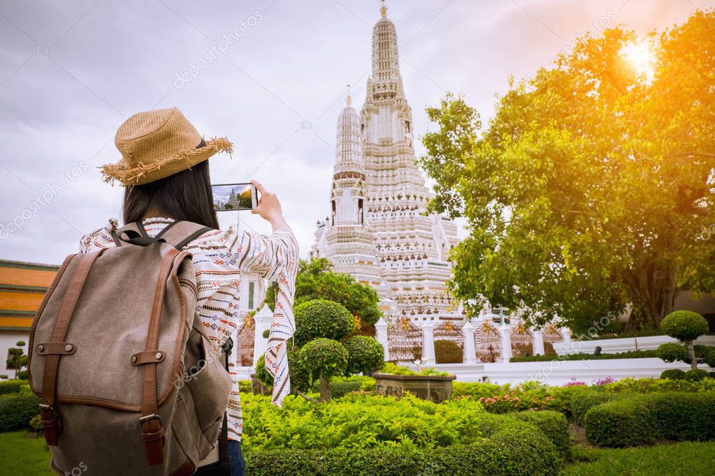 Asian woman tourists are taking photos of the Wat Arun temple on vacation Bangkok Thailand.