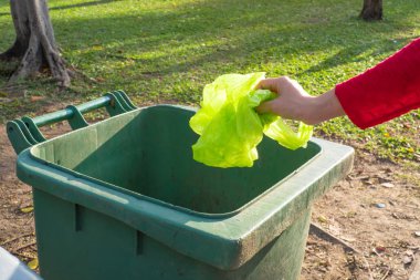 Women hand throwing plastic bag in recycling bin to help environmental protection and Waste separation reduce global warming clipart