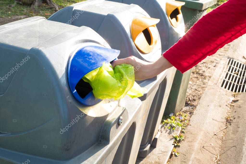 Women hand throwing plastic bag in recycling bin to help environmental protection and Waste separation reduce global warming