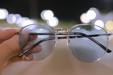Siyah gözlüklerin erkek eli var, eski bir bokeh arka planı var..