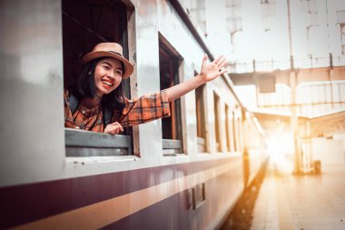 Asya genç kadın turistler trende oturup Hua Lamphong İstasyonu Bangkok Tayland bırakmak için el salladı. Tatilde Gezilecek Yerler.