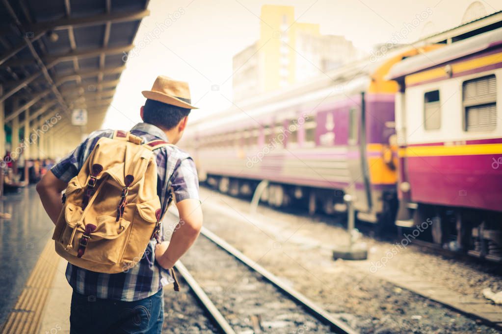 Asian male tourist standing carrying a backpack. Wait for the train at Hua Lamphong Bangkok Thailand. During his travels in vacation.