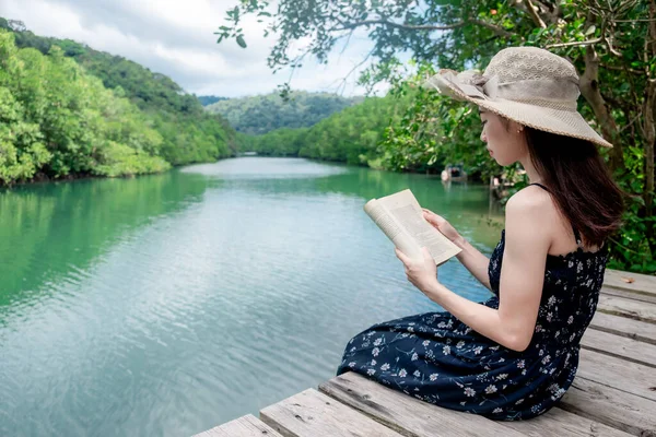 Asian women sitting reading. River view with mangrove forest. And the clear skies with beautiful clouds. Suitable for tourism, recreation and relax and intend To study knowledge