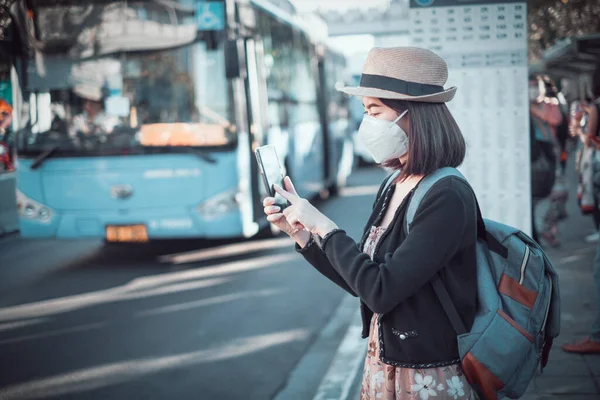 Asian woman tourists to travel. She wears a mask to protect the virus from Covid-19 and Dust pm 2.5 On his holidays. She looked at the travel map and updated the virus spread news.
