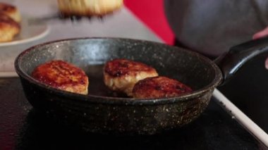 Kadın mutfaktaki sıcak tavadan köfte alıyor.