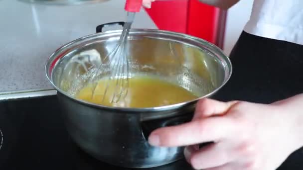 Zaman ayarlı kadın mutfaktaki ocakta kek için krema hazırlıyor. — Stok video