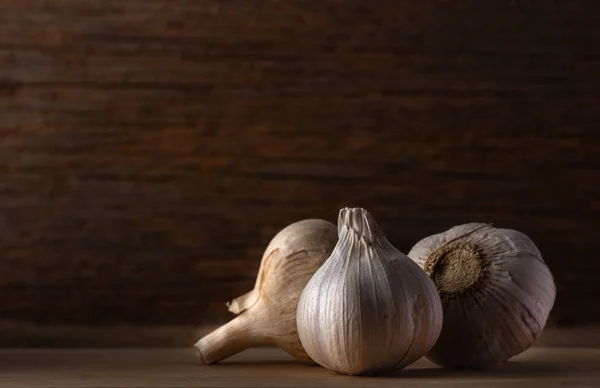 Groep knoflook hoofd op houten achtergrond, weinig licht. — Stockfoto