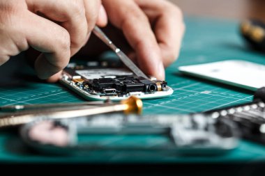 Electronics repair service. Technician disassembling smartphone for inspecting