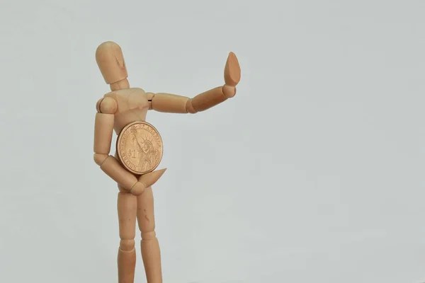 Tahta heykel Amerikan dolarını tutuyor ve dur işareti olarak elini kaldırıyor.