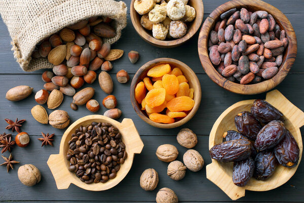 Different dried fruits, nuts and coffee beans in wooden bowls