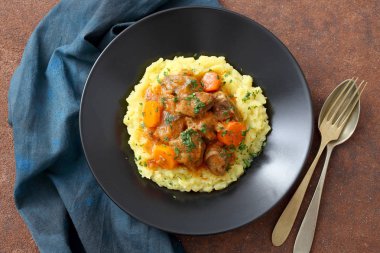 çatal ve kaşıkla havuç plaka domates soslu patates püresi ile sığır eti güveç