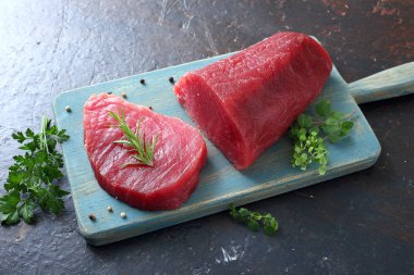 Gri arka planda tahta tahtada çiğ kırmızı ton balığının yakın plan görüntüsü