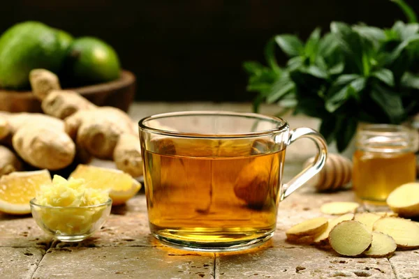 レモンとミントの入った生姜茶のグラスを木のテーブルに置いて — ストック写真