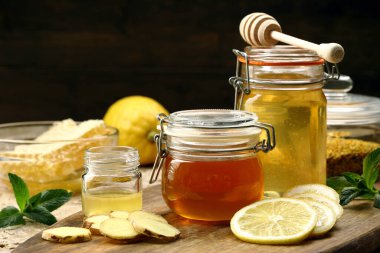 Tahta masada bal, limon ve zencefil parçaları olan cam kutular.