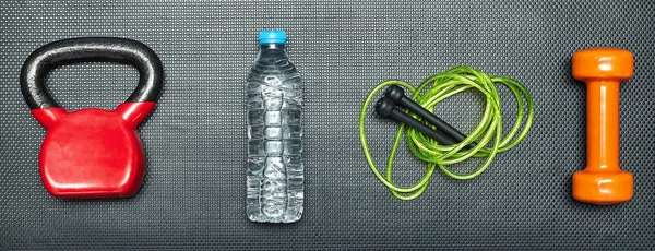 Concepto de gimnasio. mancuerna, saltar la cuerda, el peso de entrenamiento y la botella — Foto de Stock