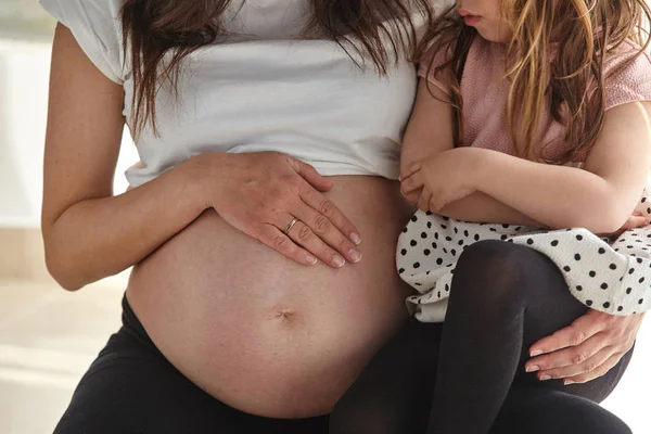 Güzel hamile kadın ve onu göbek seyir onun küçük kız.