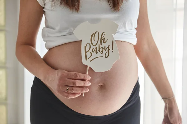 Donna incinta che tiene un cartello con scritto "Oh baby !". Foto Stock