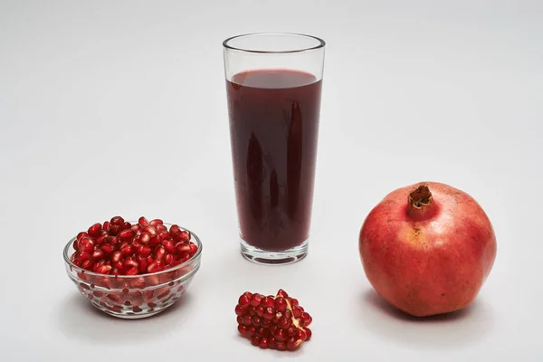 Pomegranate fruits, seeds and juice on white background. — Stock Photo, Image