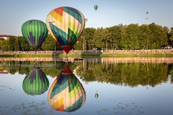 Balloons fly over the river and reflected in the water