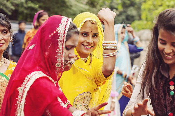 Udaipur, Rajasthan, India, February 6, 2018: Young Indian girls in traditional sari, dancing at wedding crowd on the street