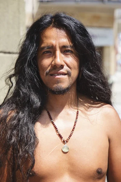 City portrait of young latino man with long hair and jewelry