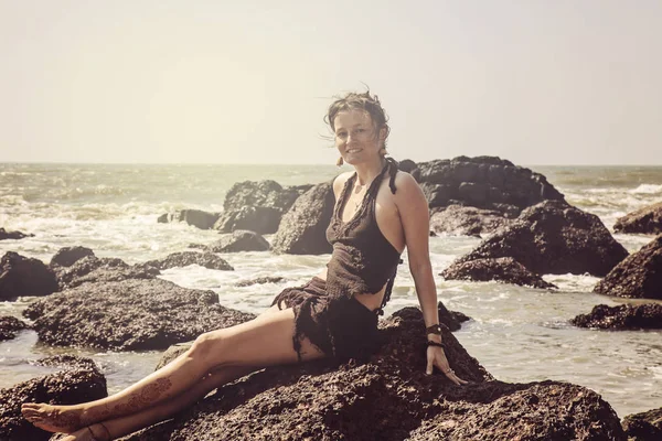 浜辺で岩の上に座っている女性 — ストック写真