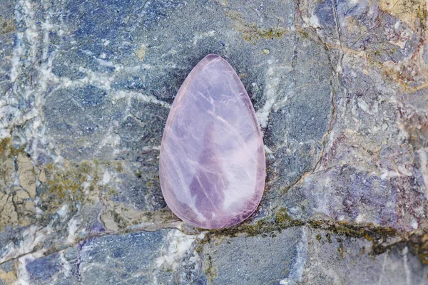 Rose quartz kaboshon on rocky background