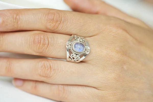 Female hand wearing silver ring with moon stone mineral