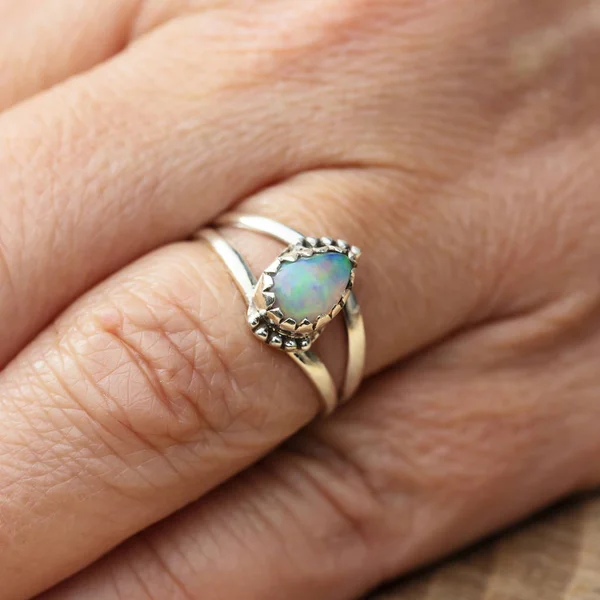 Silver ring with opal gemstone caboshon on female hand
