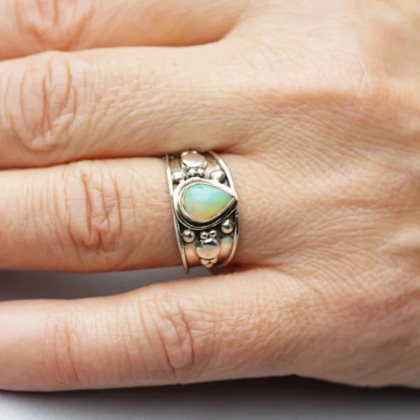 Silver ring with opal gemstone caboshon on female hand