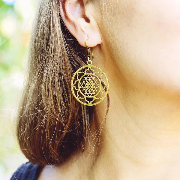 Woman wearing sacred geometry earrings closeup