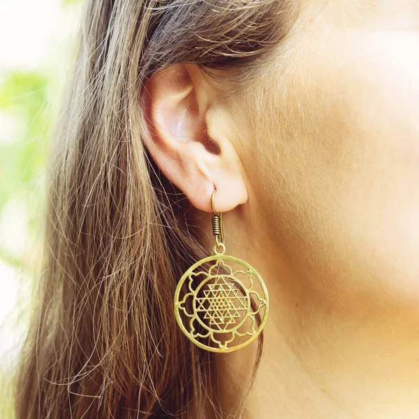 Woman wearing sacred geometry earrings closeup