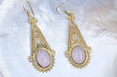 Inci arka planda mineral gül kuvars değerli taş ile Pirinç metal küpe