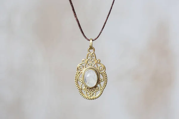 Brass metal moon stone pendant round mandala on neutral background