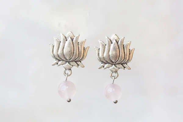 Rose quartz lotus shape earrings on neutral background